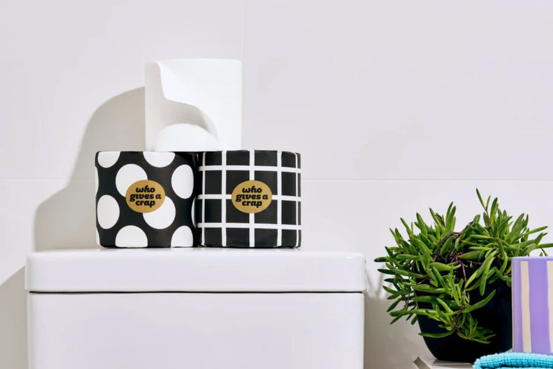 100% Bamboo Toilet Paper sitting on toilet tank in white bathroom