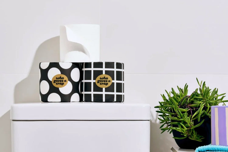 100% Bamboo Toilet Paper sitting on toilet tank in white bathroom